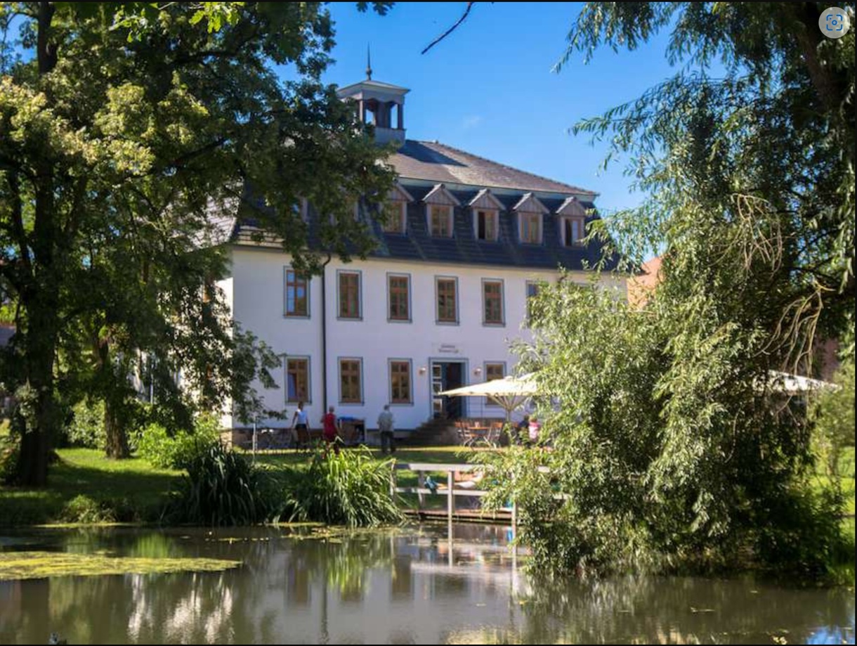 Akademie Klausenhof mit Logo Das Bild zeigt die Akademie von oben mit Wald im Hintergrund.